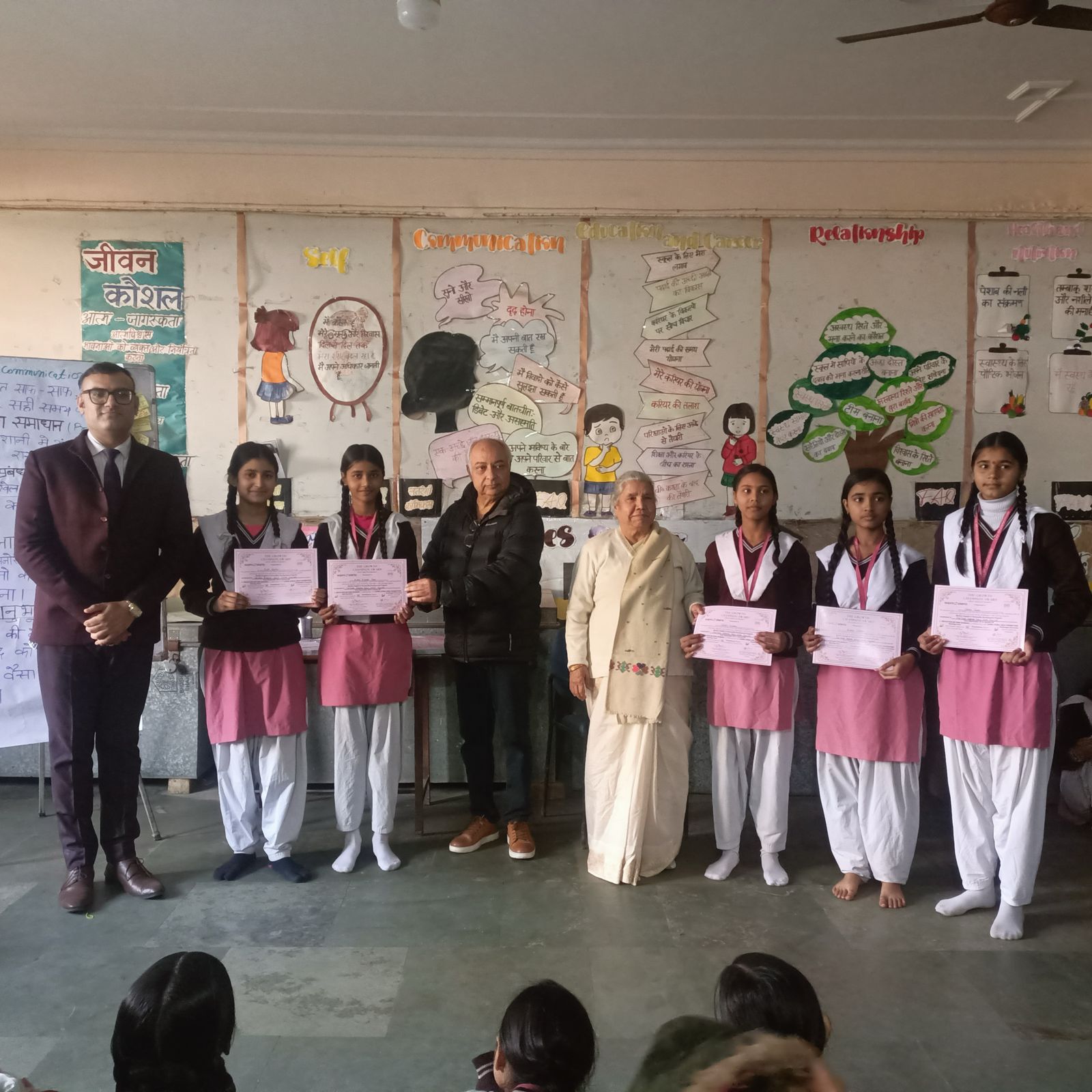 Students with guests and certificates in a school presentation space